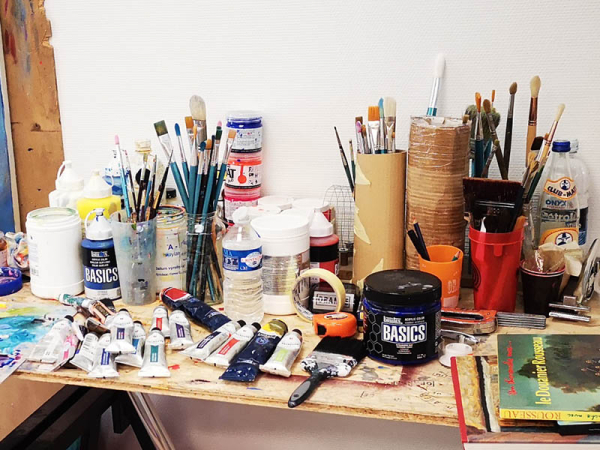 photo d'une table avec des outils et des tubes de peinture