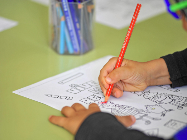 Main d'écolier remplissant un dessin