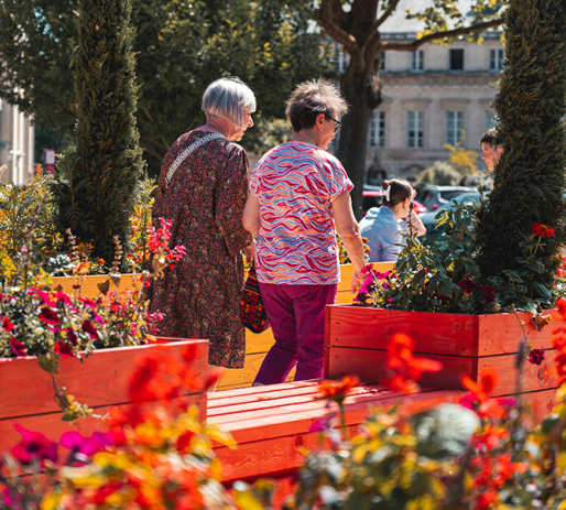 Deux femmes se promènent au milieu des bacs de fleurs des Jardins d'été, place de la République © Ville de Caen / M. Bouvier