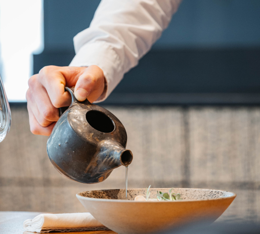 Gros plan sur une main servant une sauce dans une assiette